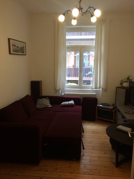 Living room with first sofa (sleeping spot for two guest). Wohnzimmer mit ausgeklapptem Schlafsofa.