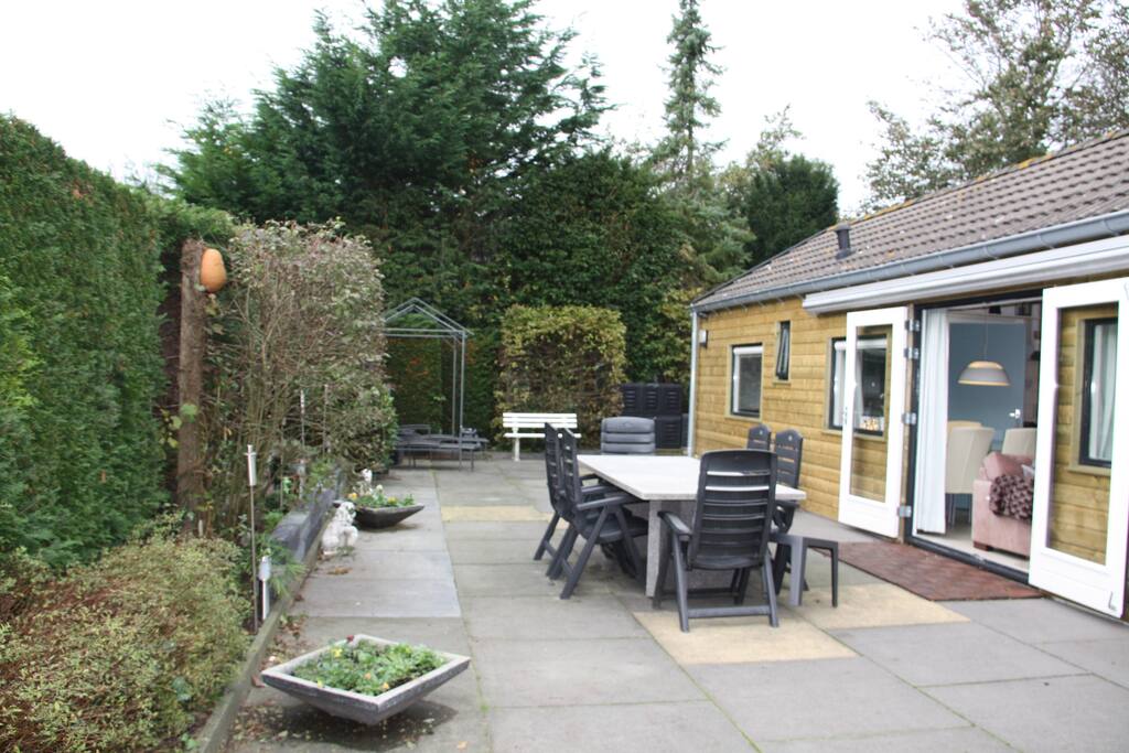 Groot besloten zonneterras met 2 ligbedden en royale eettafel met stoelen.