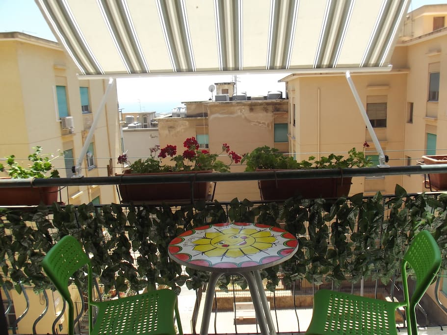 balcone attrezzato con tenda parasole e tavolo con sedie