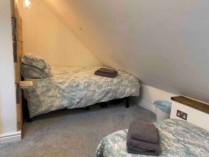 Boven slaapkamer met tweepersoonsbed - met eigen badkamer - heeft een eenpersoonsslaapbank OP AANVRAAG. * OF in plaats daarvan een reiswieg. Peuterbedbeschermer beschikbaar, maar KENNISGEVING VOORAF NODIG als alleen een tweepersoonsbed permanent. Stuur een bericht voor wat het beste werkt voor je groep.