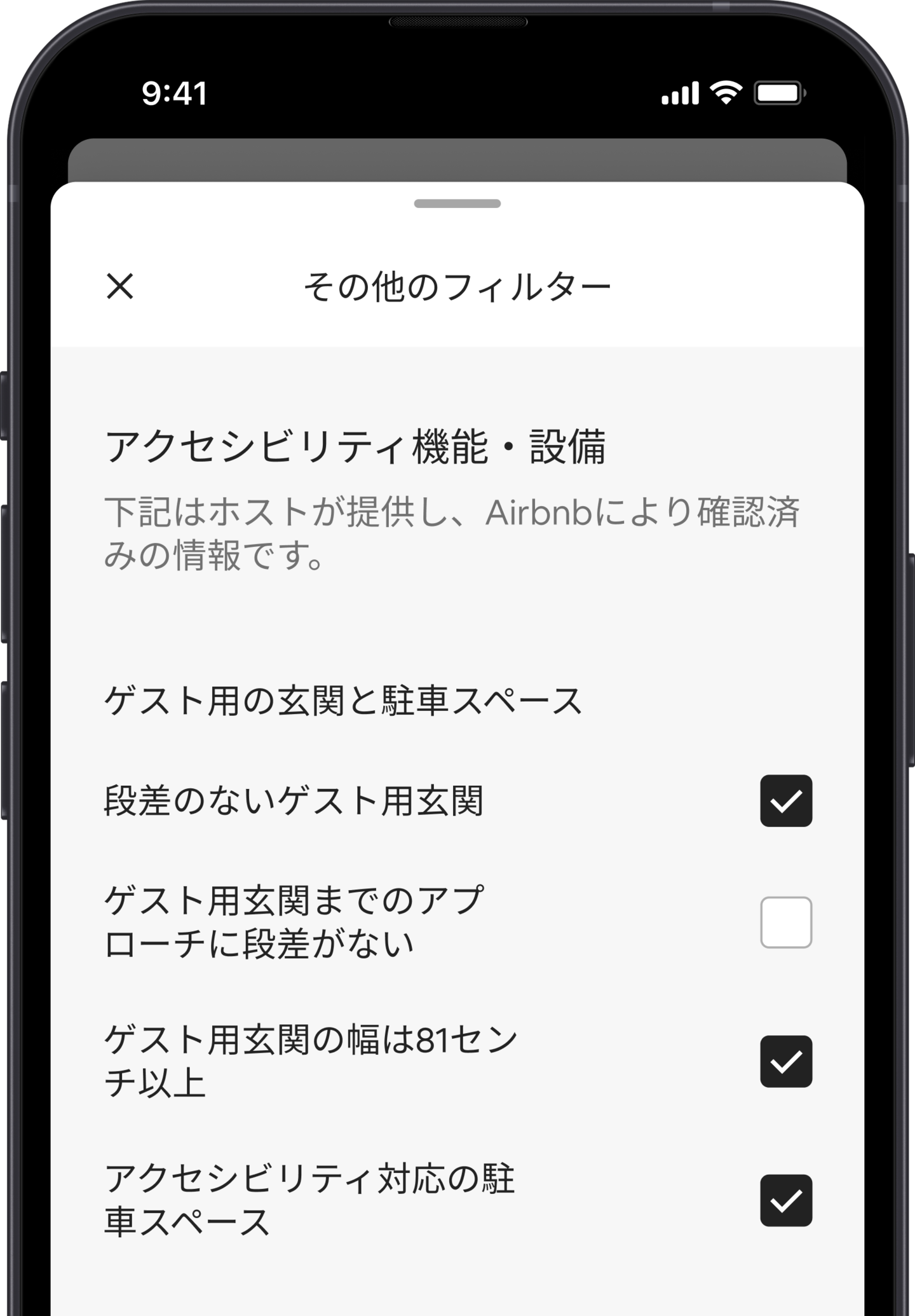 スマートフォンの画面に、多くの検索フィルターのひとつである「その他のフィルター」が表示されています。「アクセシビリティ機能・設備」という見出しのセクションがあります。その下には、アクセシビリティ機能・設備が「ゲスト用玄関と駐車スペース」のように、エリアごとにグループ化されています。必要な機能・設備を選択できるチェックボックスがあります。