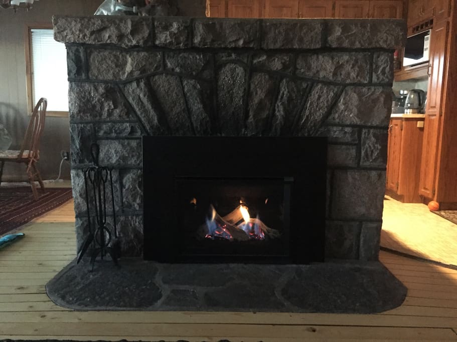 The original stone fireplace circa 1940 with a gas insert installed in 2017. A glimpse of the kitchen and dining area in the open-plan main floor of the cottage.