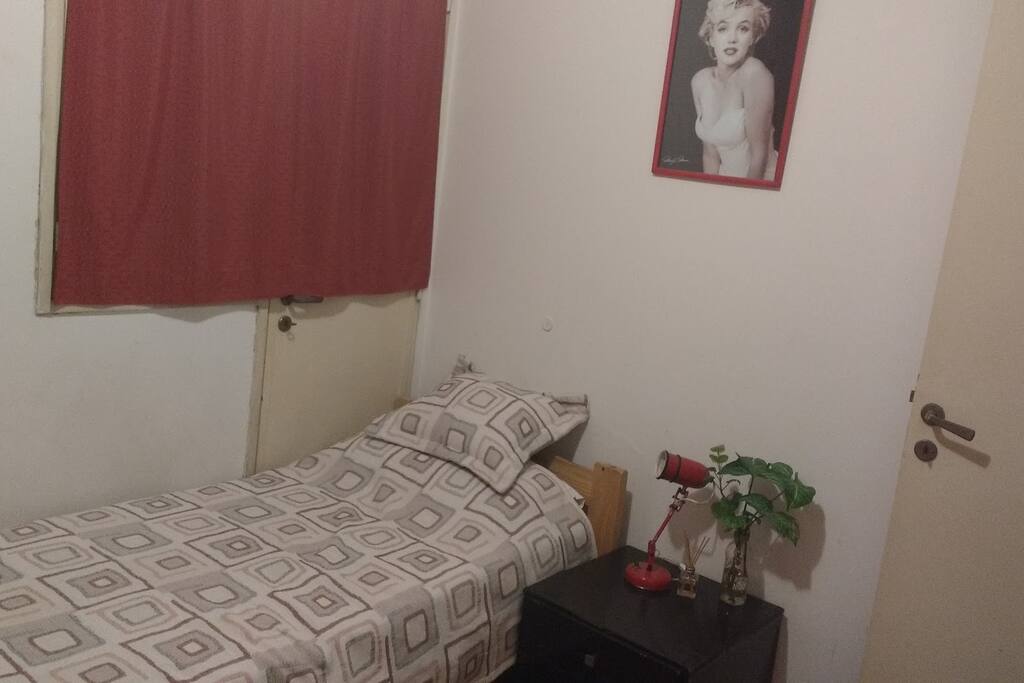 Habitación con cama de una plaza, con sabanas y colchas