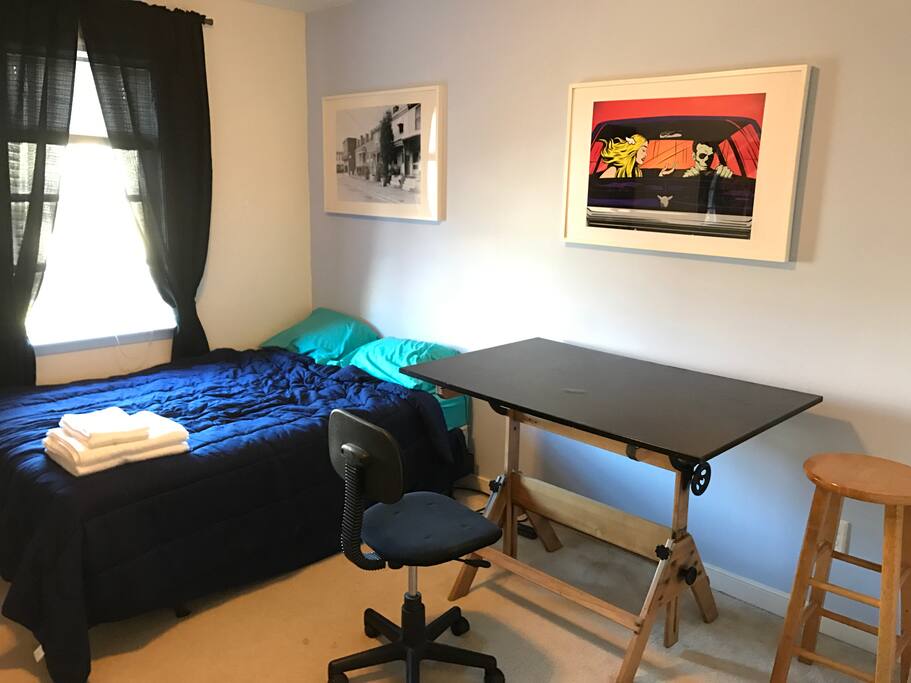 Full bed, antique drawing board, desk chair, and fresh linens