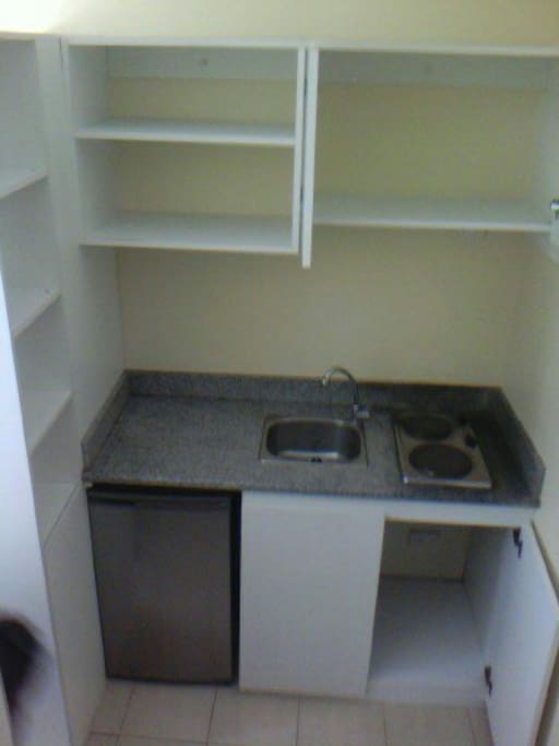 Kitchen has double burner electric stove, refrigerator, cupboards