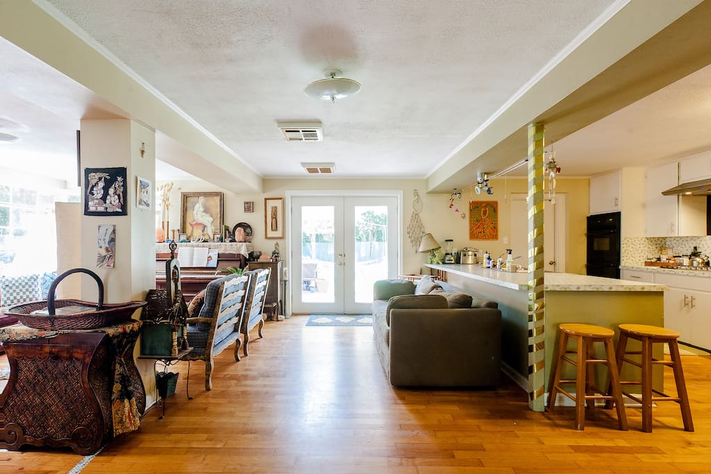 Open concept living area with another couch and bar leading into dining/kitchen to the right and back deck out of the French doors
