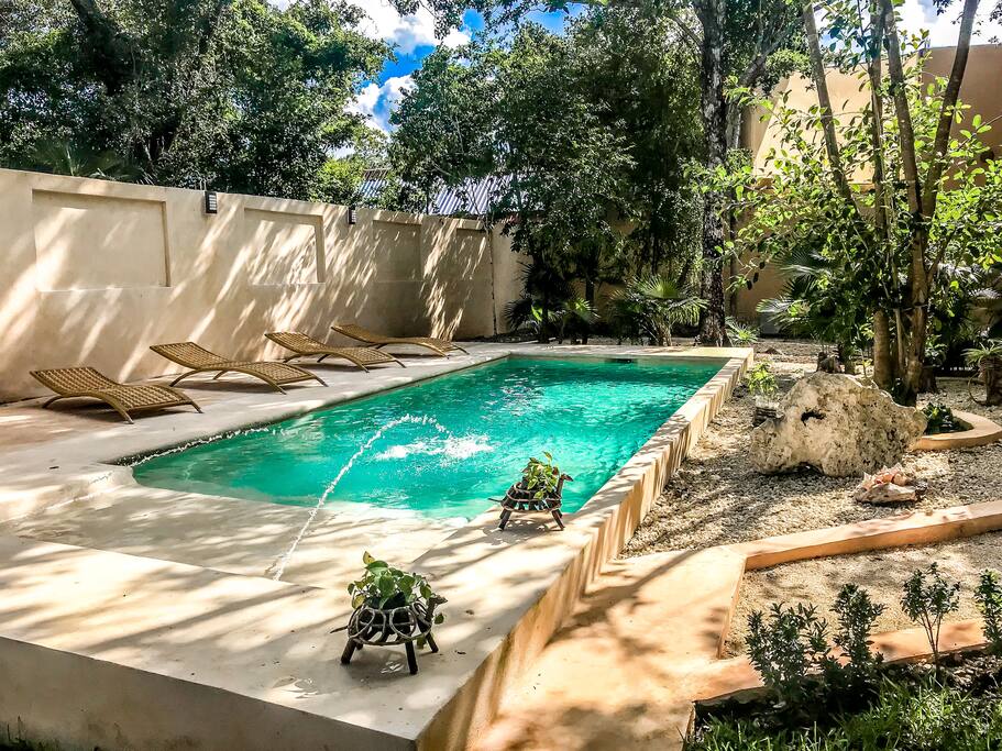 Pool area with sun beds, garden and local deco.