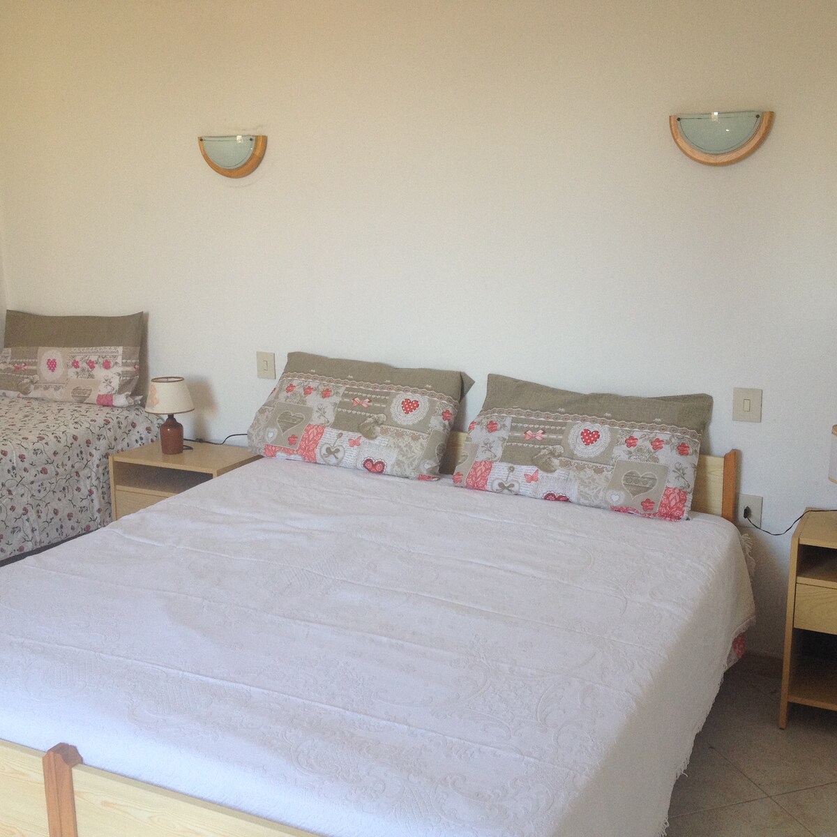 ห้องนอนที่กว้างขวางและสว่างสดใสพร้อมเตียงคู่และเตียงเดี่ยวที่มีหน้าต่าง 2 ประตู