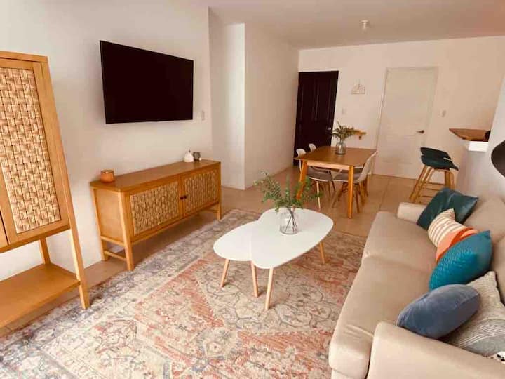 Sala con televisión, aire acondicionado, en espacio abierto con el comedor, y acceso directo por puertas de vidrio a la piscina privada.