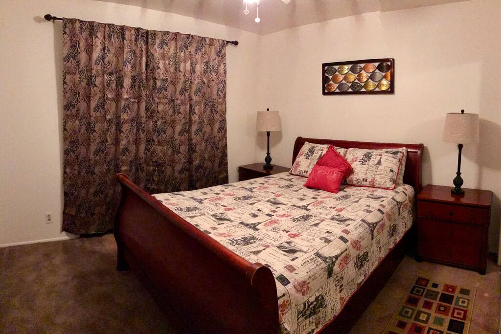 Spacious room with a queen size bed, two night stands, and window to make the room airy