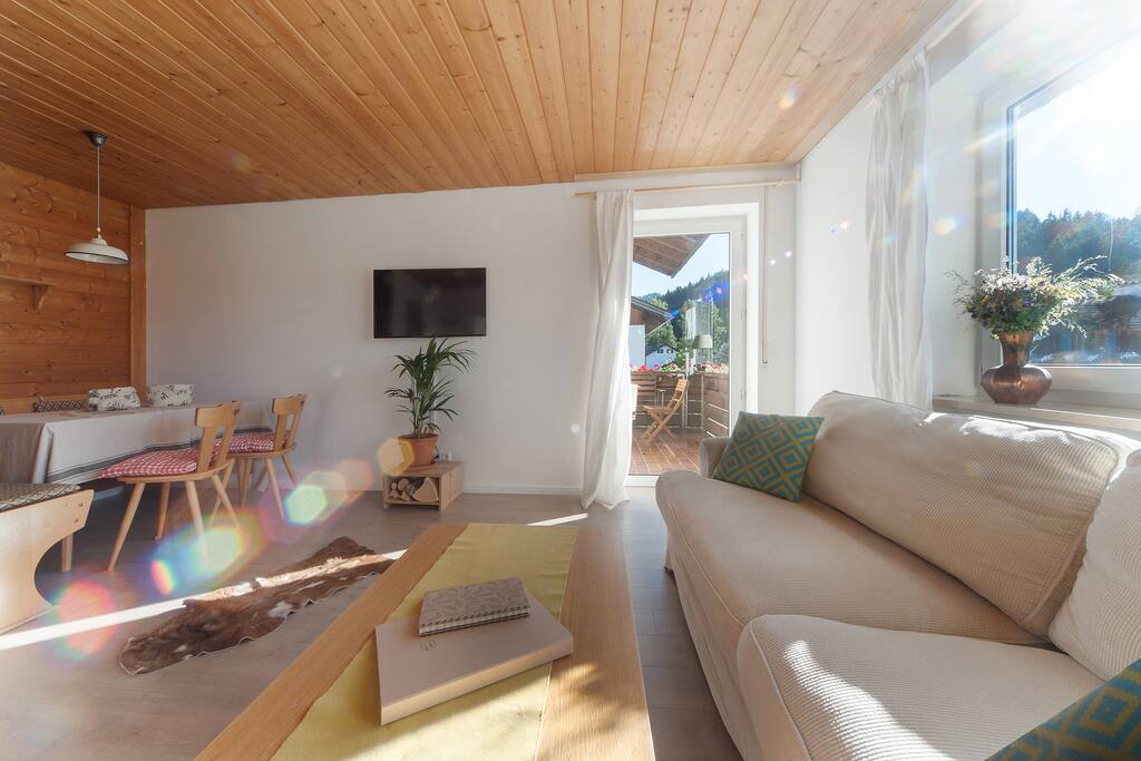 Wohnzimmer mit Couch, TV und gemütlicher Essecke