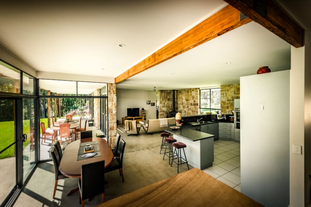 Huge open living dining and kitchen opens to outdoor veranda, lawns and forest.