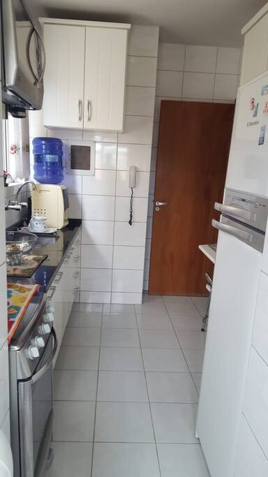 Cozinha completa, fogão, forno elétrico, microondas, geladeira e utensílios.