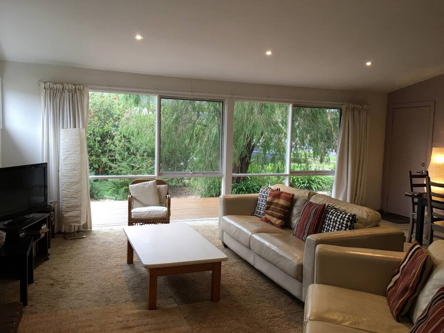 Large bright and comfy lounge with warm carpets and a glowing fireplace. Large wall of windows overlooking the front deck and garden but still maintaining privacy due to the well tended garden.