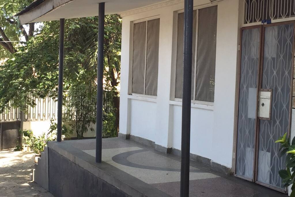 This is a photo of the front porch and main entrance. You can see a bit of the parking area and the garden.