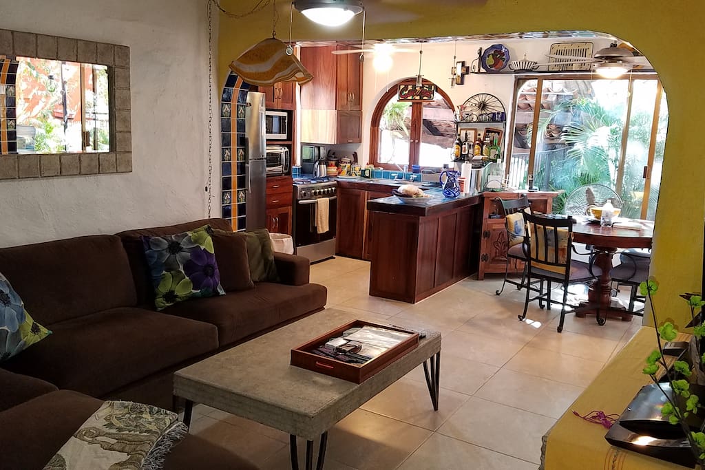 View of the living room, kitchen, and and dining area from bedroom door. Large sectional sofa.