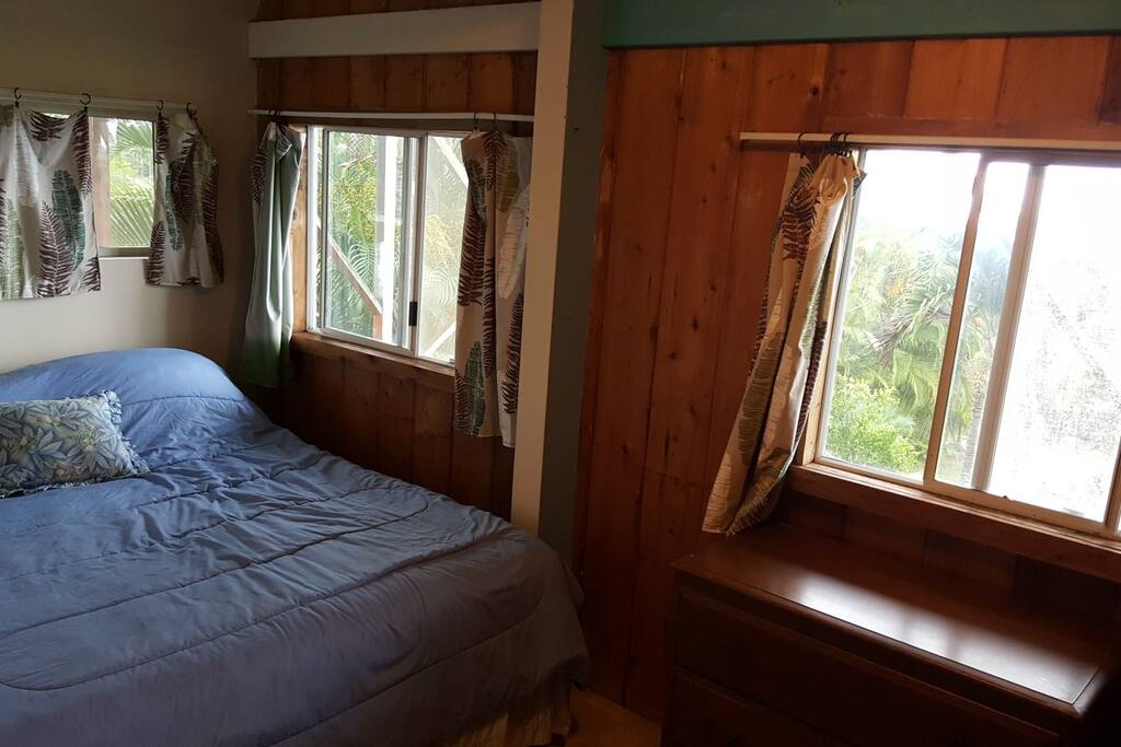 king bedroom with three windows, two with ocean views