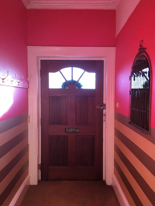 Your first port of call: the entrance hall with Osborne and Little striped wallpaper and my favourite raspberry red