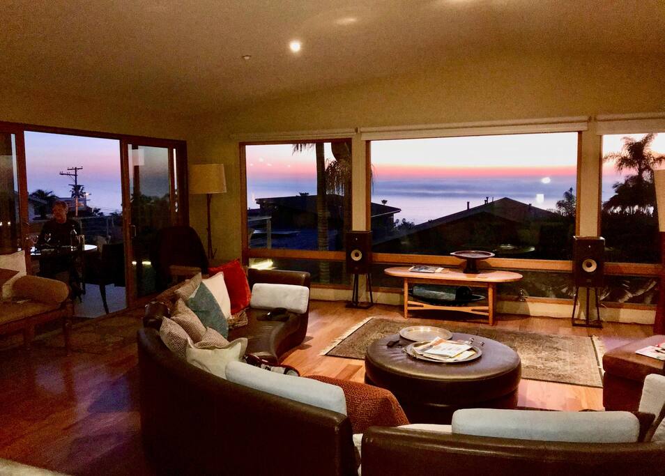 Spacious living room with two comfortable, stylish leather chairs, round leather couch, and wall of windows facing South & West.
