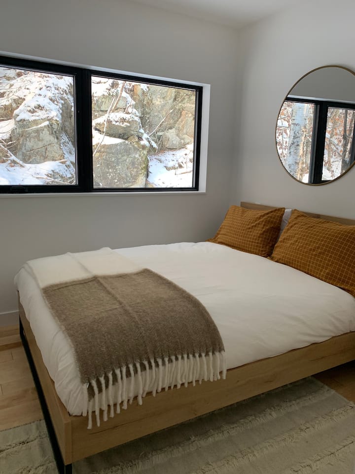 Chambre 1 - Lit Queen - Literie en lin lavé haut de gamme. Couette et oreillers en duvet d'oie. Vue immersive sur la falaise et la montagne.