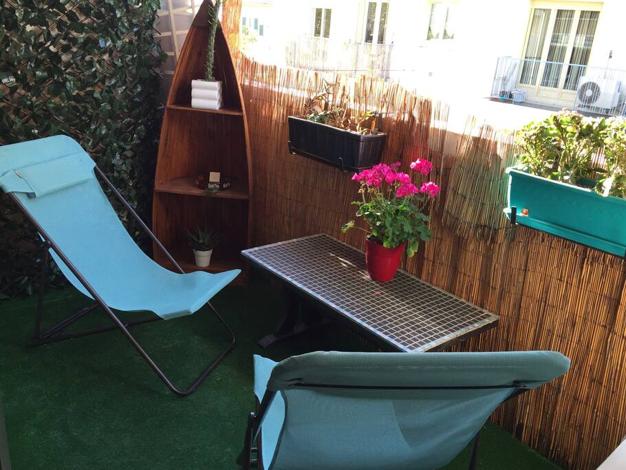 Balcon loggia chaleureux, avec pelouse artificielle, store et deux chaises longues pliables