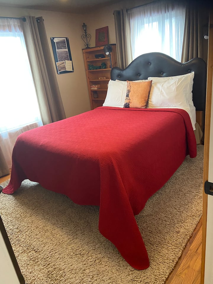 غرفة "القطار". سرير بحجم كوين مع رفوف كتب وطاولة جانبية صغيرة ؛ مقعد مقعد صغير وخزانة ملابس ومرآة وخزانة مع حاملين للأمتعة وشماعات.