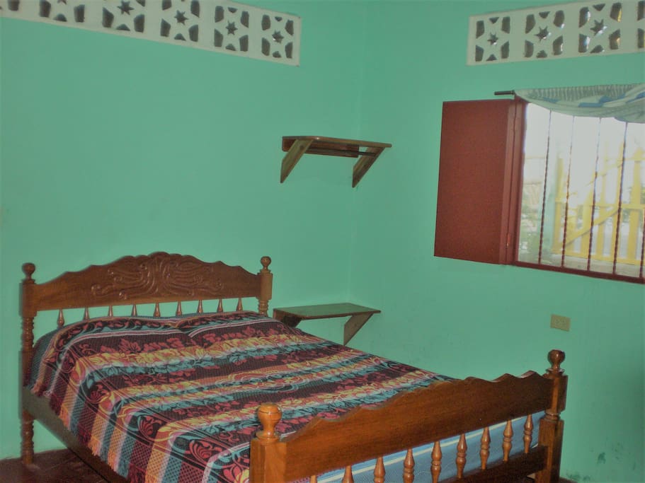 2 Bedrooms to accommodate 4 guests. Front bedroom with double bed, screened window with metal bar protection, shelves, fan, place to hang clothes.