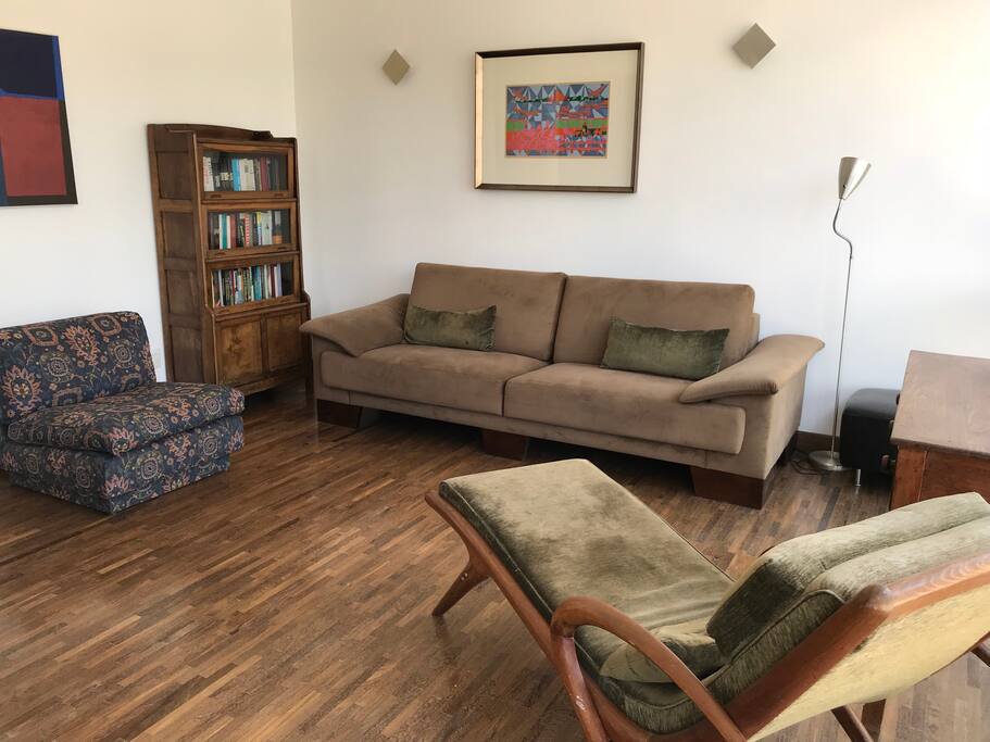 Sala de estar vista da porta da varanda. Não fique em um estúdio apertadinho - desfrute do pé direito alto e dos 140m2 deste apartamento. Tudo desta foto estará disponível para seu uso (vide detalhes sobre o sofá-cama de solteiro na legenda da foto principal).