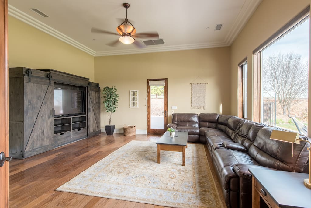 Upscale theater room with 65" TV and leather sectional sofa.