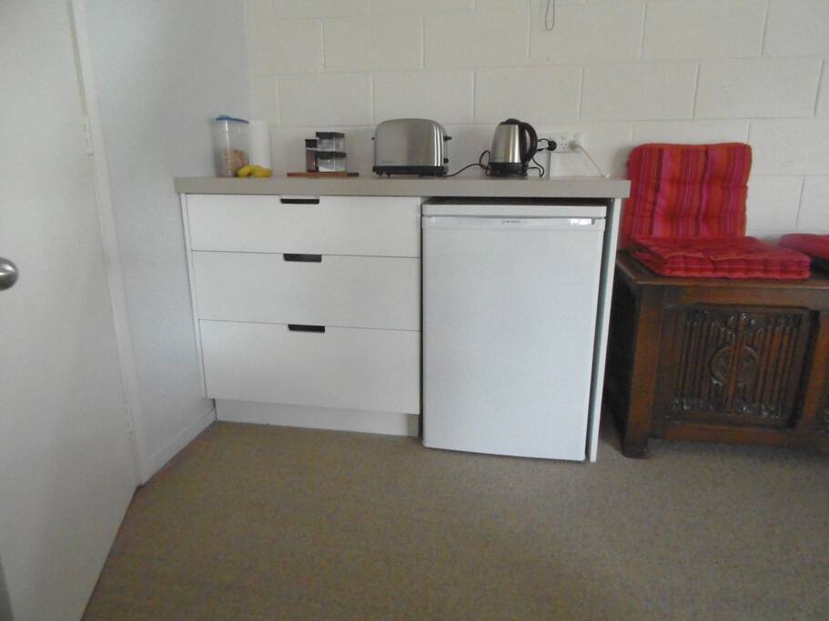 Kitchen unit with fridge under, jug microwave and toaster.