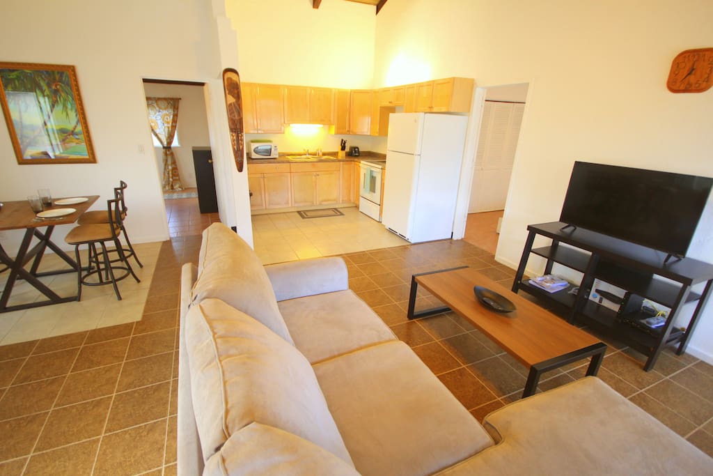 There is a full kitchen, dining area, and a living area with flat screen TV and comfortable couch.