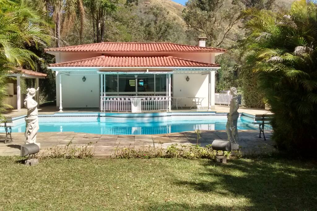 Piscina com vestuários; salão de festas; churrasqueira e sauna localizados no mesmo nível da casa principal e de hóspedes.