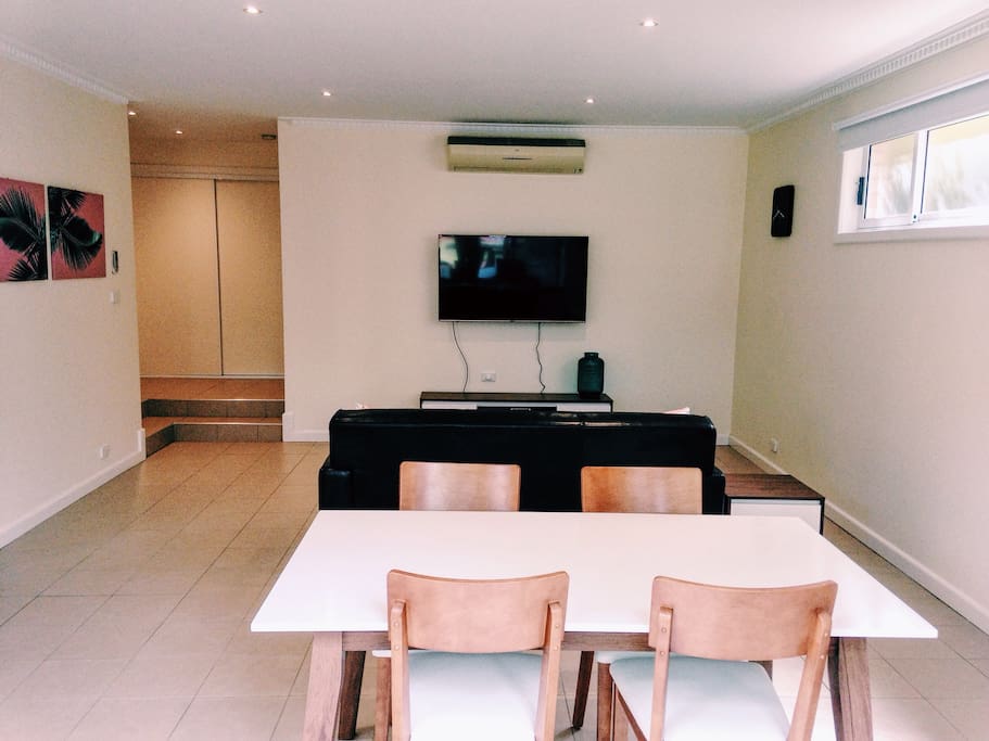 Living area contains modern comfortable furnishings including large dining table, comfy lounge and huge 55inch TV
