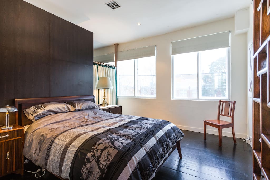 First bedroom with Queen bed, tree views, spacious, wooden floors.