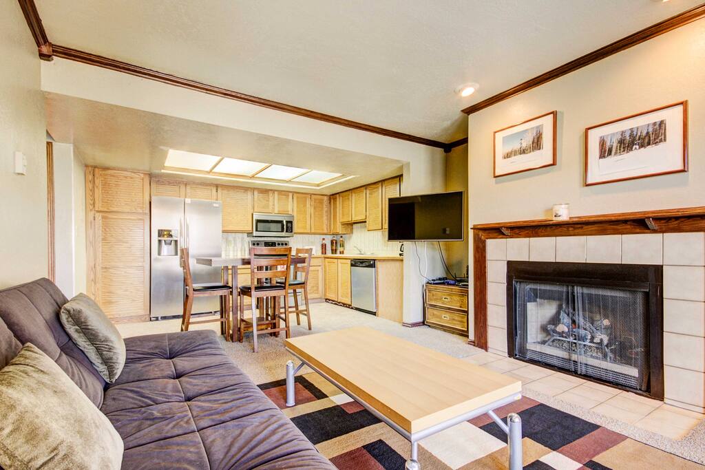 The living room welcomes you with large windows, a futon couch, fireplace, and flat-screen cable TV.