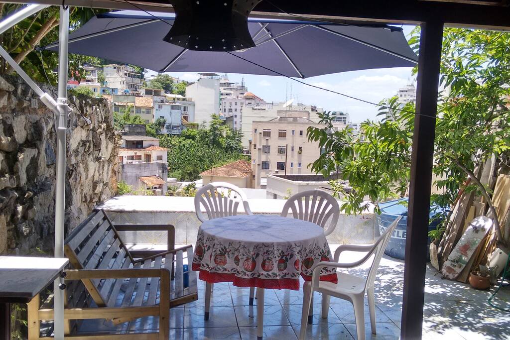 Vista, mesa com cadeiras, bancos e guarda sol.