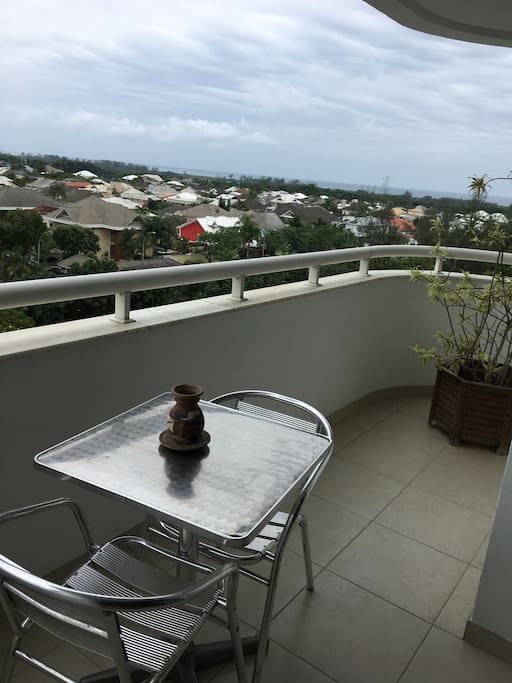 Varanda com mesa e 2 cadeiras com vista para o mar