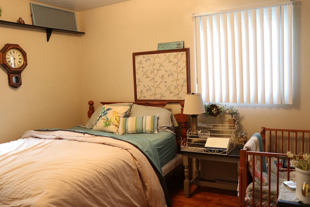Guest bedroom with small crib. There is also a small chair and a closet.