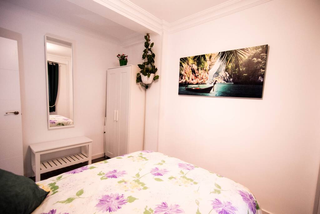 Cama, mesillas, un armario y banco para maletas.