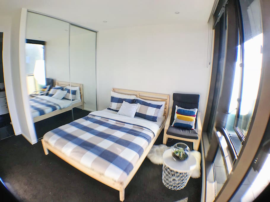 Spacious bedroom with king bed, built-in wardrobe, armchair and little coffee table.