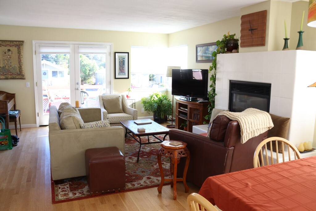 Open living room with dining area, gas fireplace, French doors to large wood deck