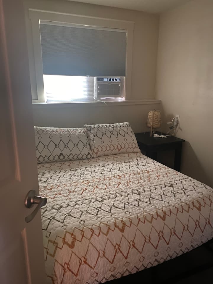 חדר שינה ראשון עם מיטה בגודל מלא ותריסים שחורים. 