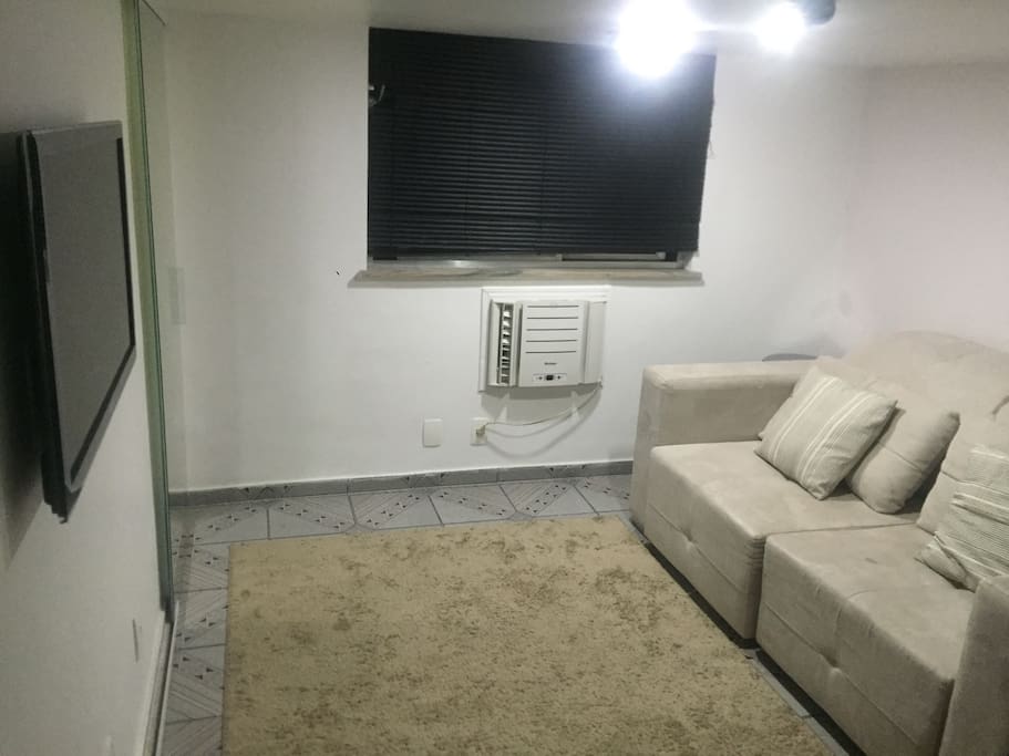 Na sala de estar do apartamento, sofá-cama, ar-condicionado e TV de plasma