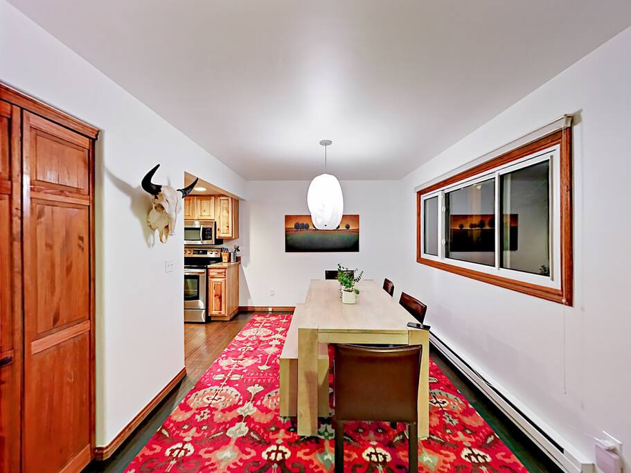 Enjoy meals in the dining area with a vibrant rug and 8-seat table.