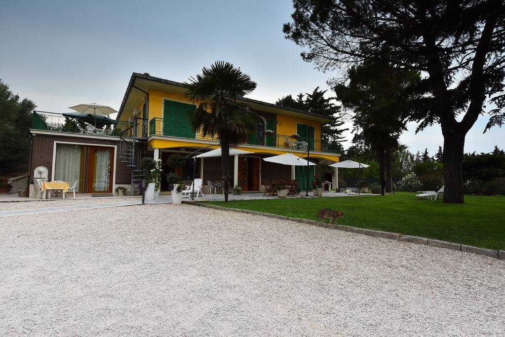 Esterno della casa , situata sulla collina che domina il centro commerciale, al cui interno è ubicata la camera verde. L'ospite può comodamente usufruire del posto auto all'interno del giardino recintato