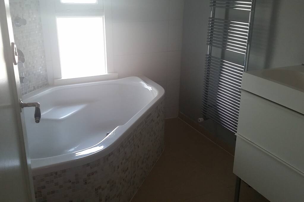 badkamer met groot bad, stortdouche en 2 persoons wastafel.
Vloerverwarming en radiator
