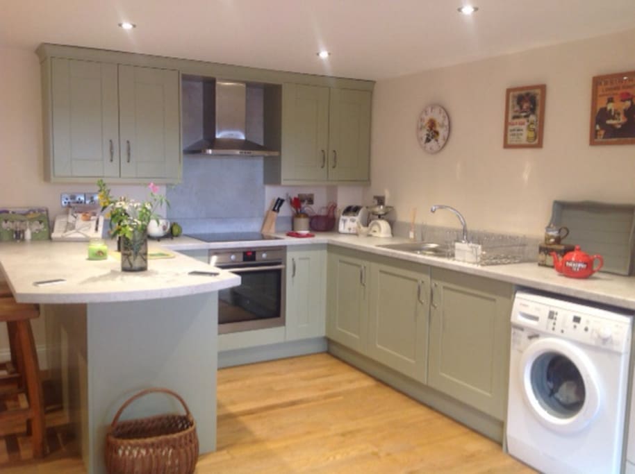 Modern newly fitted kitchen with all the essentials including induction hob, microwave, fridge, tassimo coffee machine, washing machine and dryer.