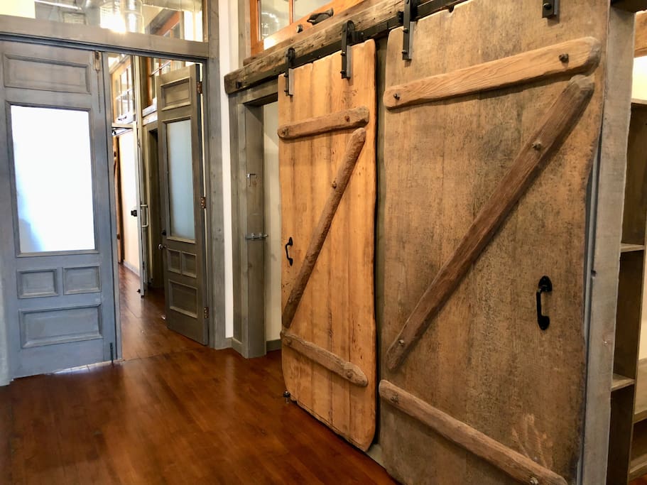 The 9 foot tall dual entry doors are the original main entry doors to the building that have been saved and repurposed. Dual sliding barn doors were custom made of aged white oak by a local artisan wood worker.