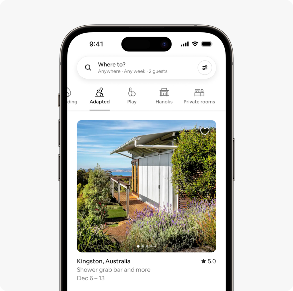 A laptop and a phone show the Airbnb homepage with two rows of homes from a new Airbnb Winter Release category called Adapted, which features wheelchair-accessible homes that have confirmed step-free access to the bedrooms and bathrooms.