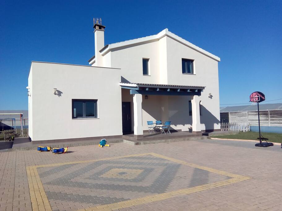 Frontal de la casa con parking grande y porche.